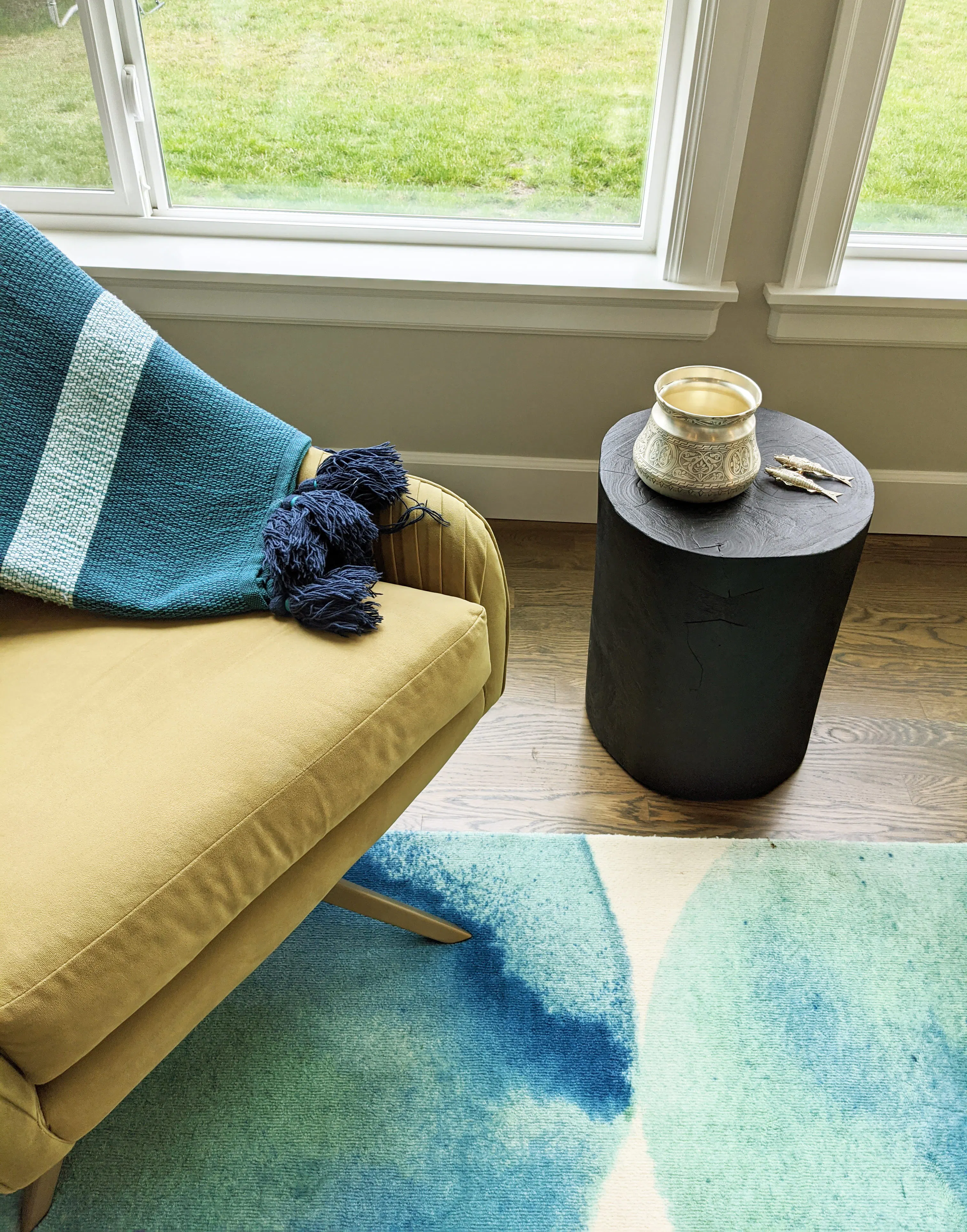 In this vignette of a living room designed by Persimmon Design, the softly reflective silver vessel introduces a quiet glimmer against the deeply matte wood table, illustrating how even small moments of polish can bring depth and contrast to a composition grounded in honed, tactile surfaces.