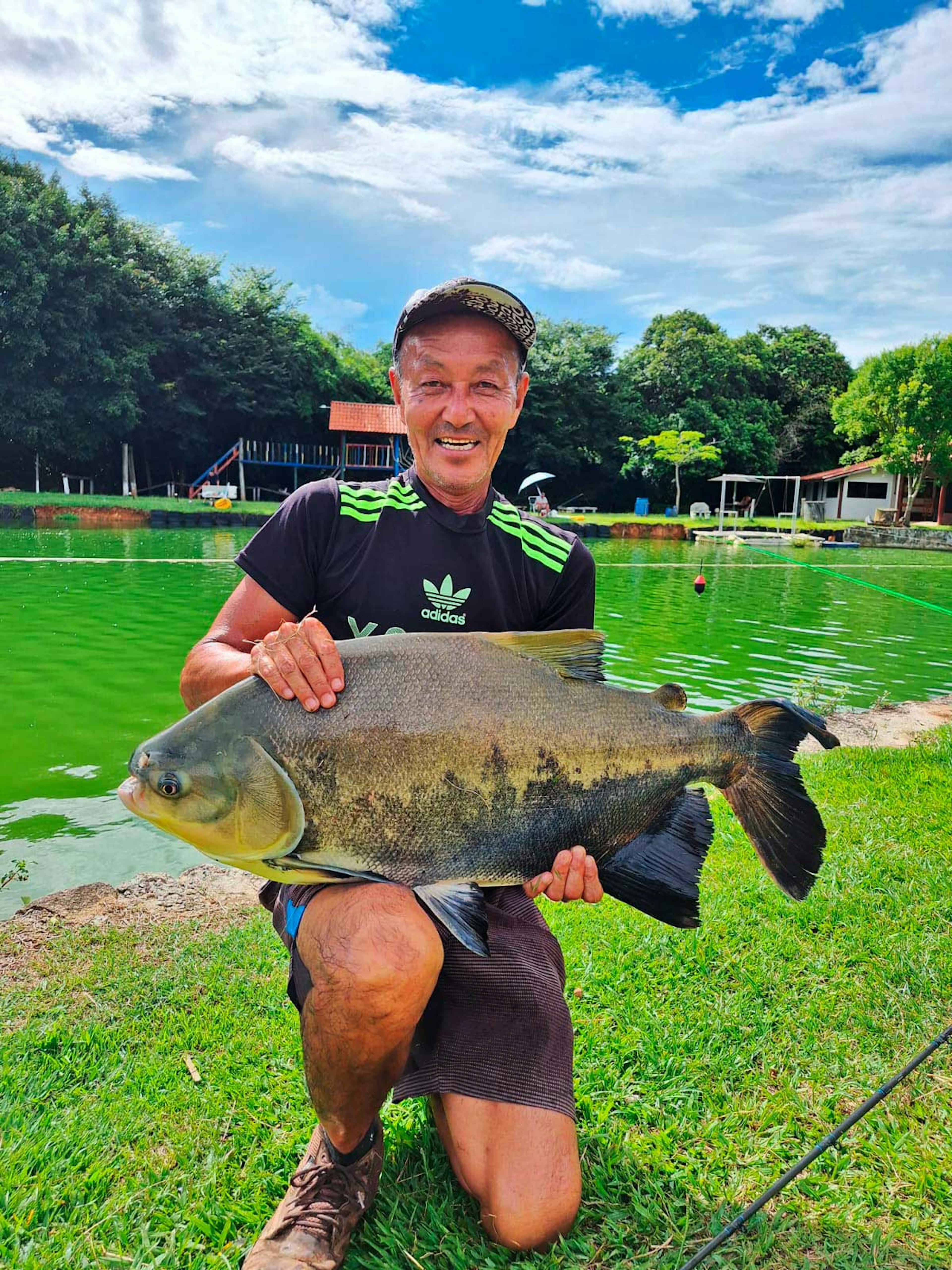 Homem segurando peixe grande no Pesqueiro Nenê Oliani