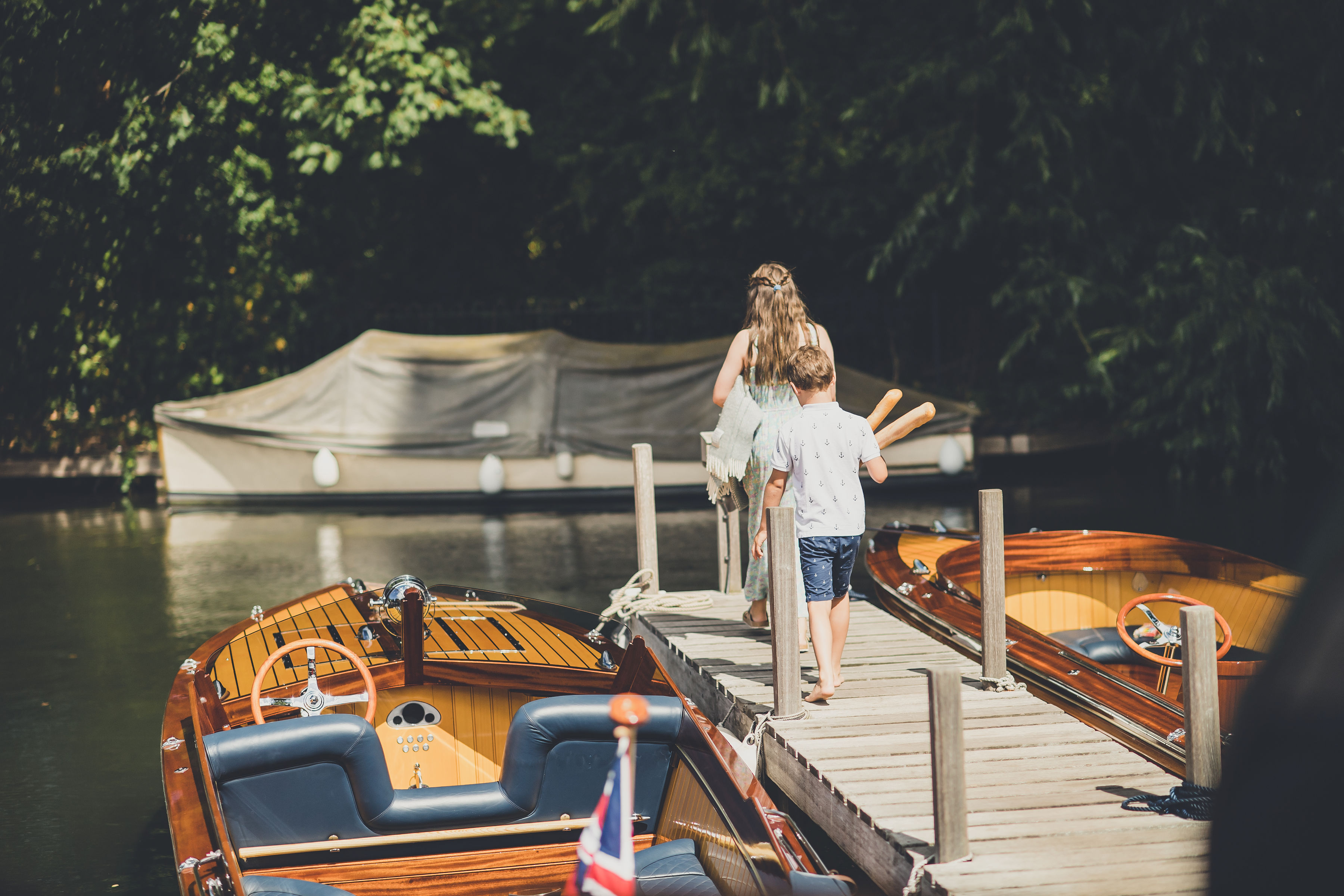 Luxury boating, people walking along Freebody's boatyard moorings ready for a day on the river on board Freebody slipper launch