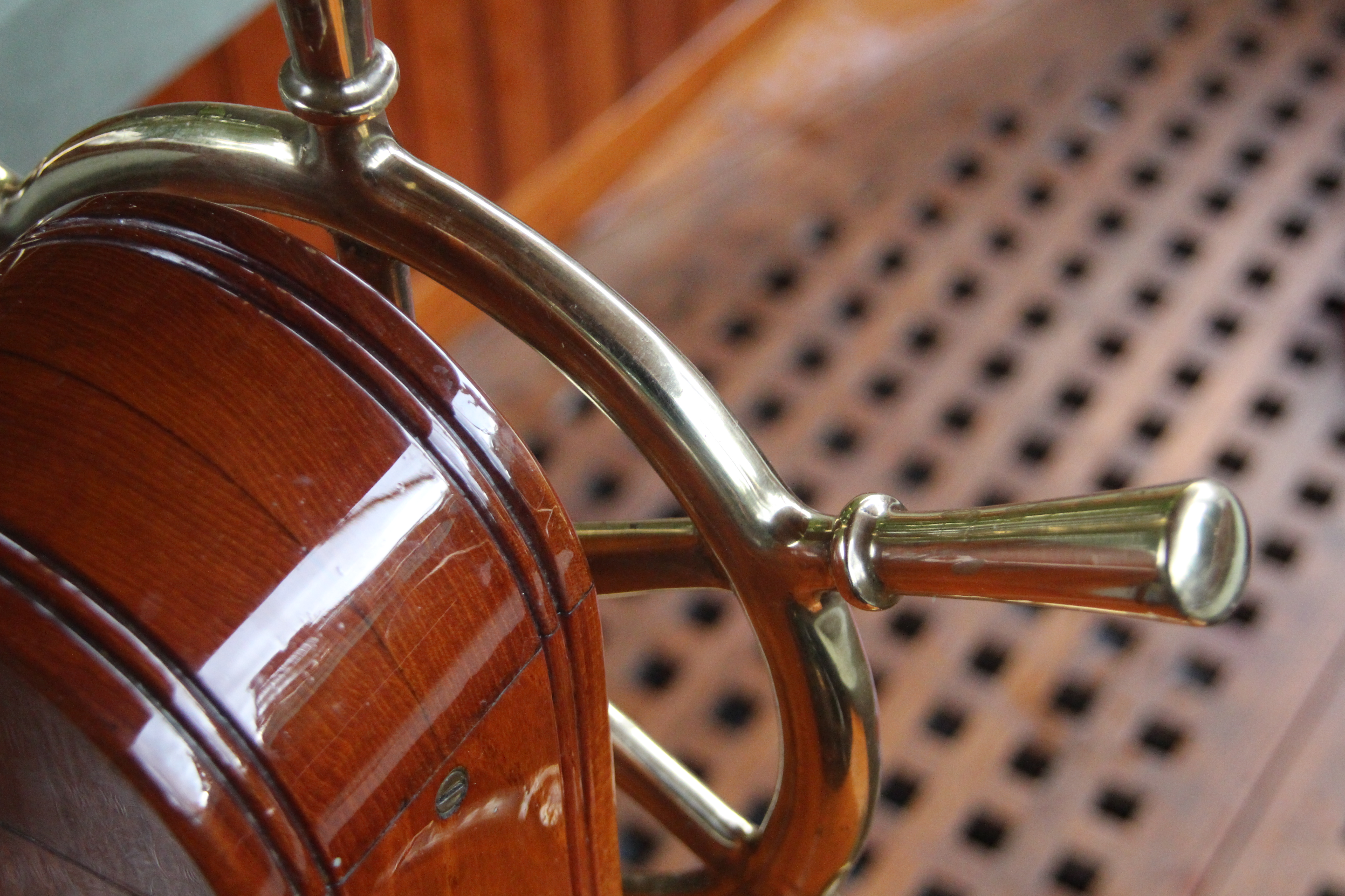 Steam launch for sale, detail showing brass steering wheel and teak floor grating
