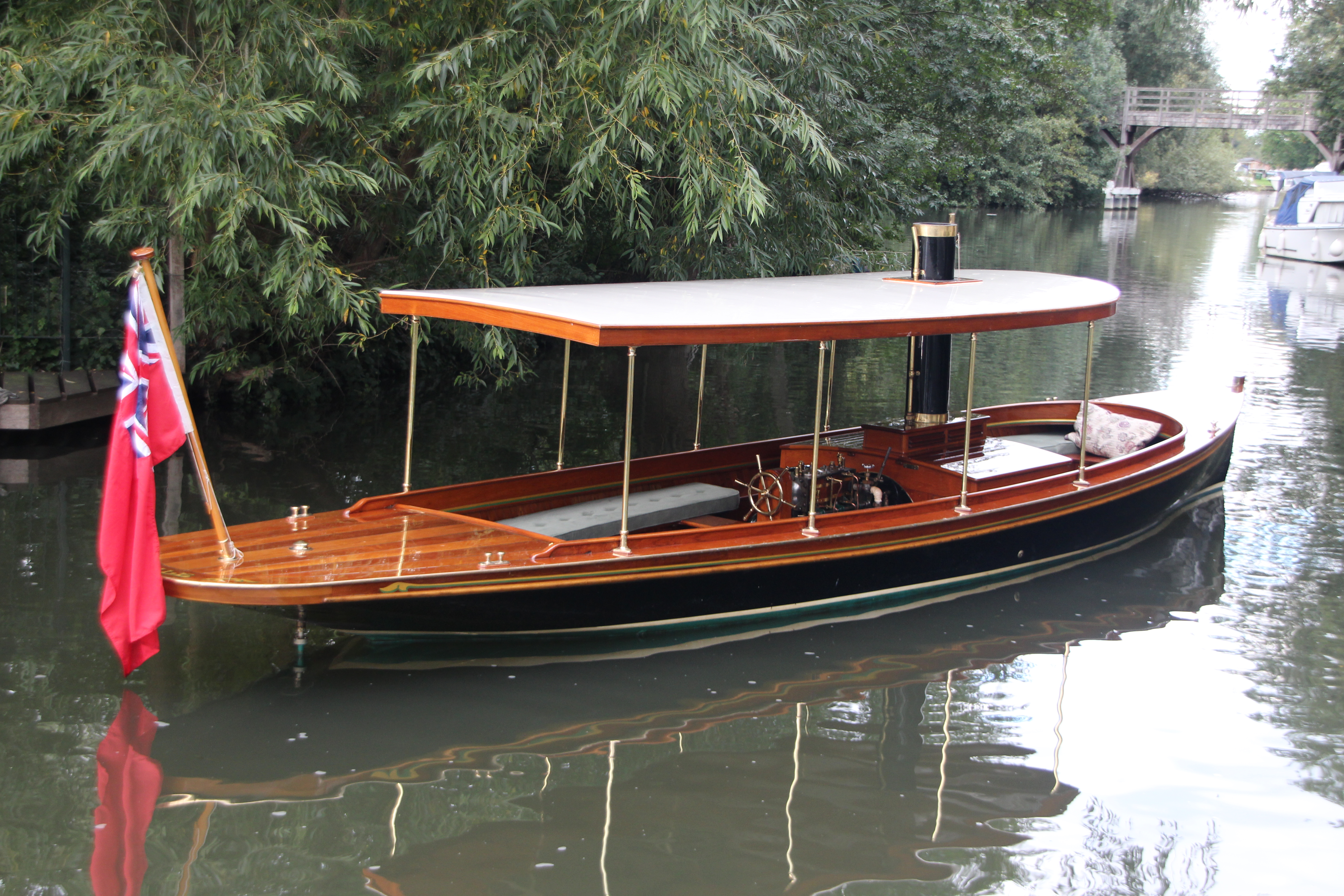 Steam launch for sale, side profile view from stern with red ensign flag 