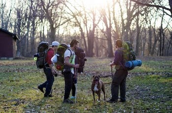 group of people with backpacks and a dog hiking
