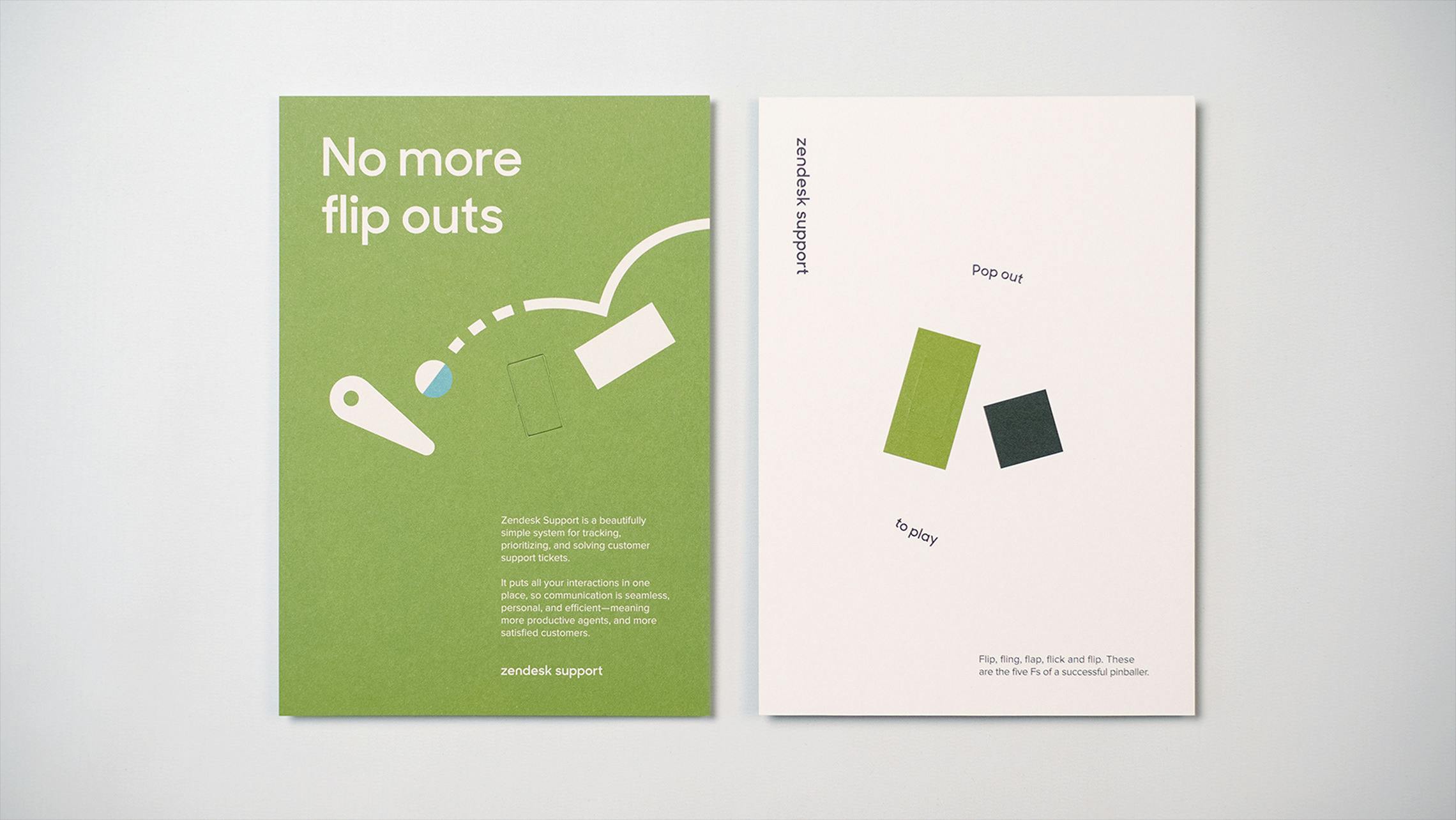A side-by-side view of two Zendesk marketing cards against a white background. The left card is green, with the headline 'No more flip outs,' a pinball graphic, and a description of Zendesk Support. The right card is white, labeled 'Zendesk Support,' and shows two perforated, pop-out shapes (one green, one dark grey) with the instructions 'Pop out to play.