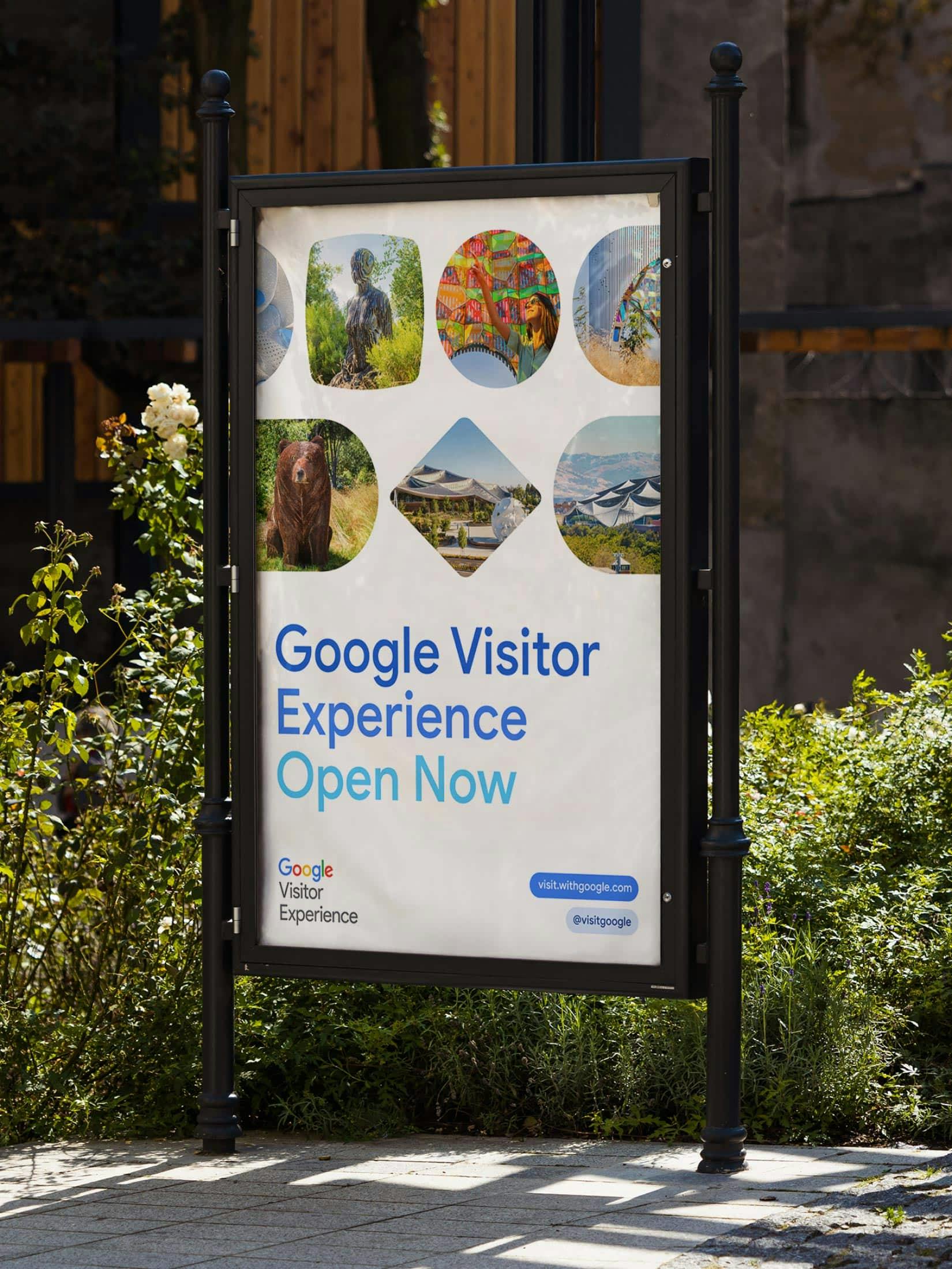 Outdoor sign promoting the Google Visitor Experience, featuring a collage of colorful attractions and landmarks including a bear sculpture, vibrant artwork, and the distinctive canopy roof of the Google Bay View campus.