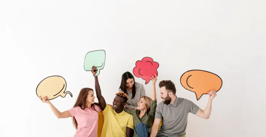 Grupo de pessoas sorrindo e levantando placas com ícones de pensamento e emoções, representando comunicação, ideias e sentimentos em uma ilustração conceitual sobre interação e conversa.
