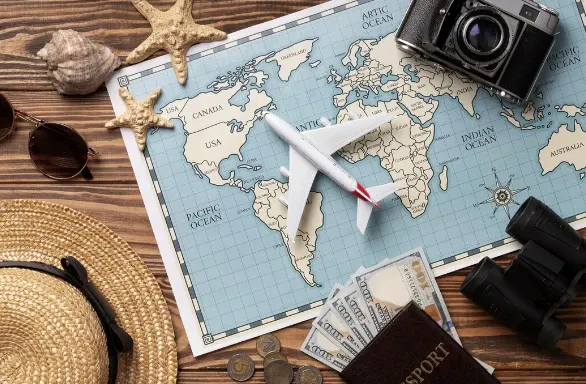 Mapa-múndi aberto com avião de papel, passaporte, moedas e binóculos sobre mesa de madeira, com elementos de viagem e navegação marítima.