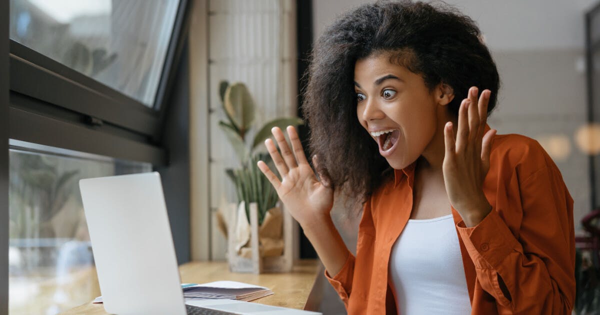 Uma mulher sentada à mesa com o laptop aberto, concentrada em seu trabalho.