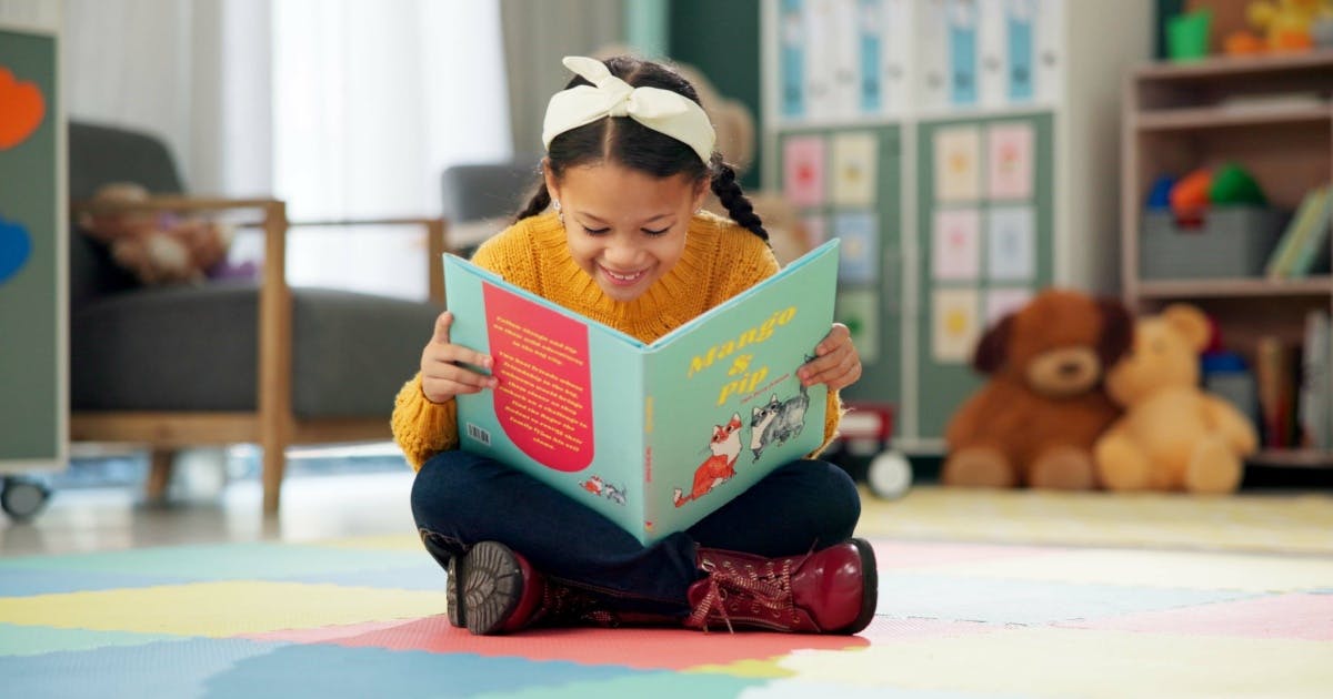 Menina jovem lendo um livro em sala de aula, concentrada e envolvida na leitura, enquanto aumenta seu vocbulário.