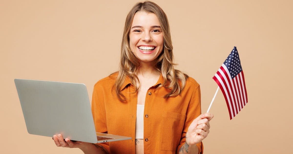 Mulher sorridente segurando uma bandeira americana e um laptop para aprender inglês, transmitindo alegria..