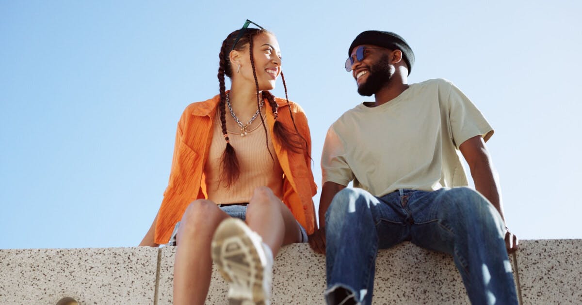 Um homem e uma mulher sentados em um muro, conversando e desfrutando do momento juntos.