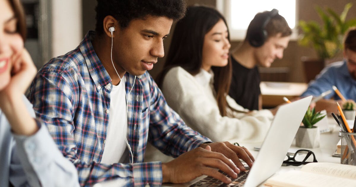 Um grupo de pessoas concentradas, trabalhando em laptops em um ambiente colaborativo e produtivo.