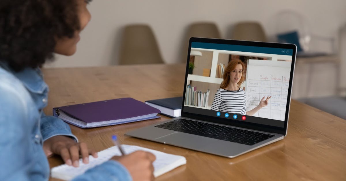 Mulher usando um laptop para fazer uma videochamada com alguém em um curso de inglês online.