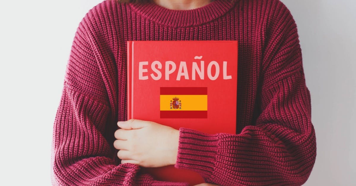 Mulher segurando um livro com a bandeira da Espanha para aula de espanhol.