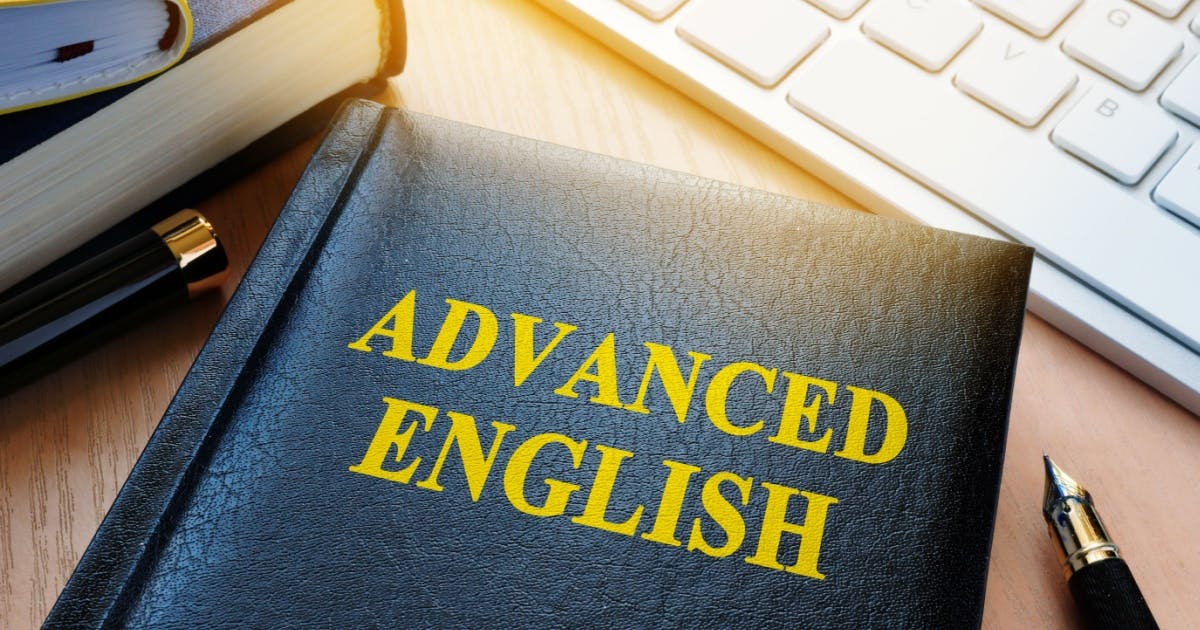 Livros de níveis de inglês em cima de uma mesa e um deles com "Advanced English" estampado na capa, com objetos ao lado.