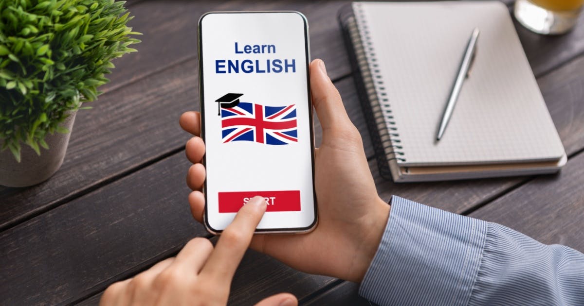 Homem mexendo em um aplicativo para aprender inglês, com a frase "Learn English" na tela com uma bandeira da Grã-Bretanha.