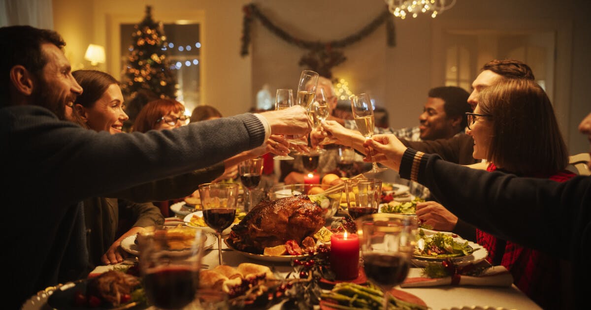 Um grupo de pessoas brindando durante um jantar de Natal, celebrando a união e a festividade da ocasião.