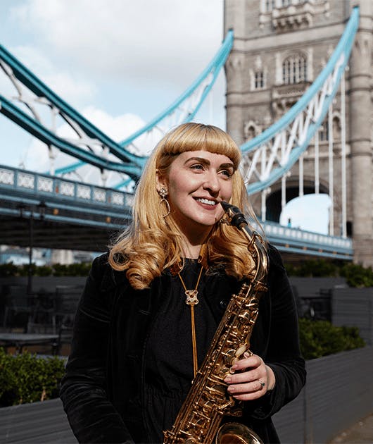 Mulher loira tocando saxofone nas ruas