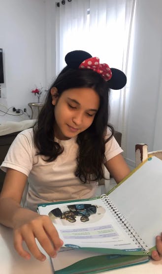 Foto da Milena, Aluna da Phenom BC, folheando o livro da Phenom.