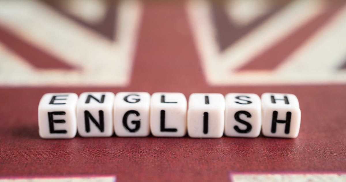 A palavra "English" formada por cubos com letras em cima da bandeira do Reino Unido. 
