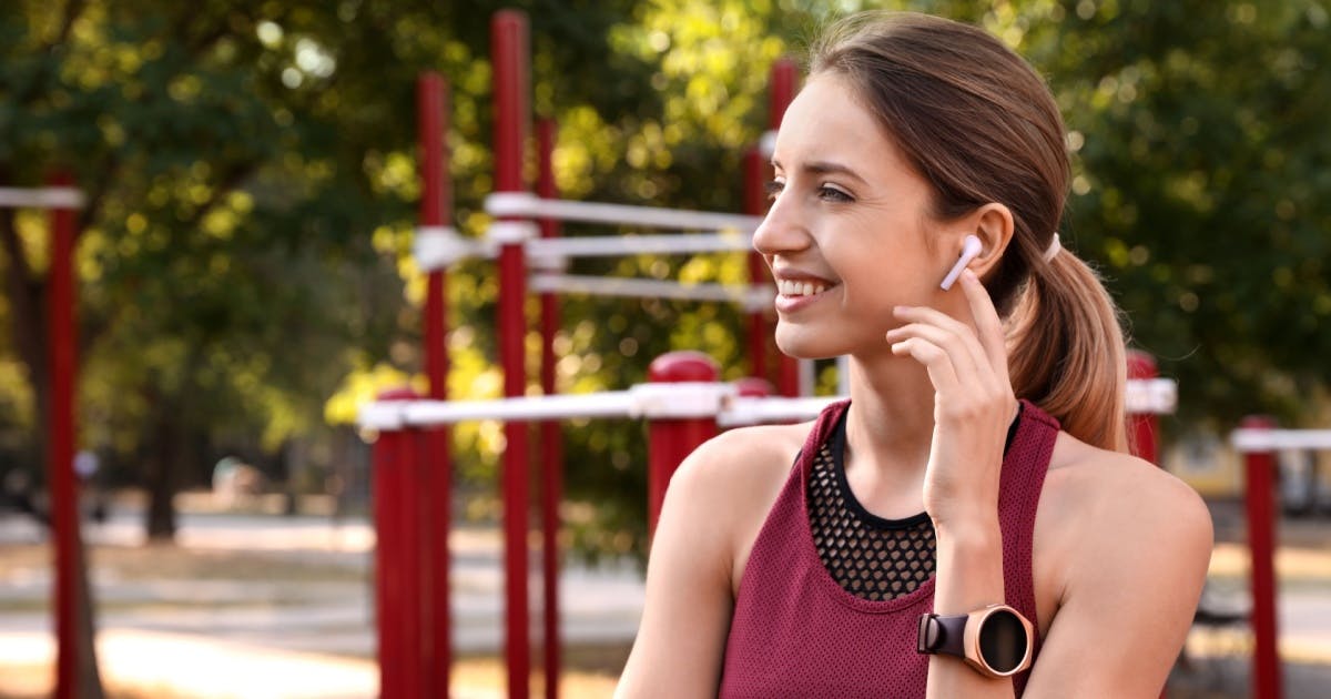 Mulher usando fones de ouvido para ouvir podcast em inglês — ferramentas de idiomas para treinar escuta.
