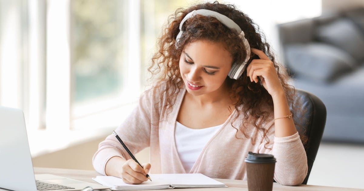 Músicas para aprender inglês: estudante com fones de ouvido estudando inglês com música no notebook.
