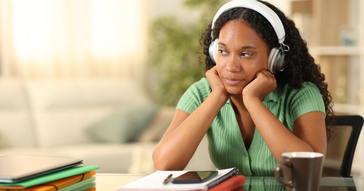 Músicas para estuda: estudante concentrado com fones de ouvido e caderno.