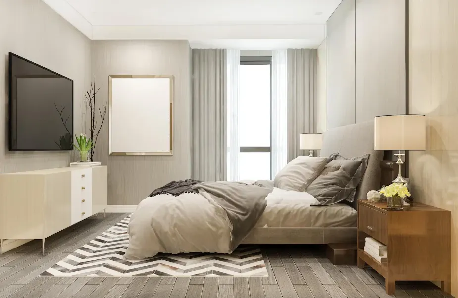 Quarto moderno e aconchegante com cama queen, roupa de cama cinza, criado-mudo de madeira, luminárias e quadro na parede, além de painel com espelho e cortinas listradas.