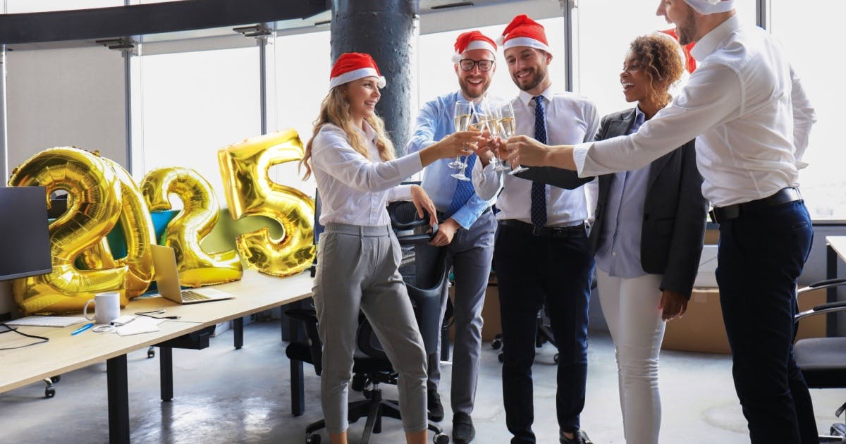 Uma equipe comemorando a chegada do Ano-Novo com bebidas no escritório, brindando a temporada de festas de fim de ano.