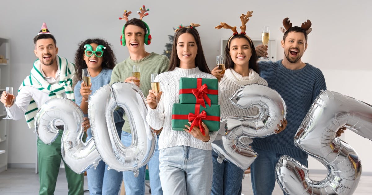 Grupo de pessoas alegres segurando presentes de Natal e números festivos, celebrando o espírito de Ano-Novo juntos.