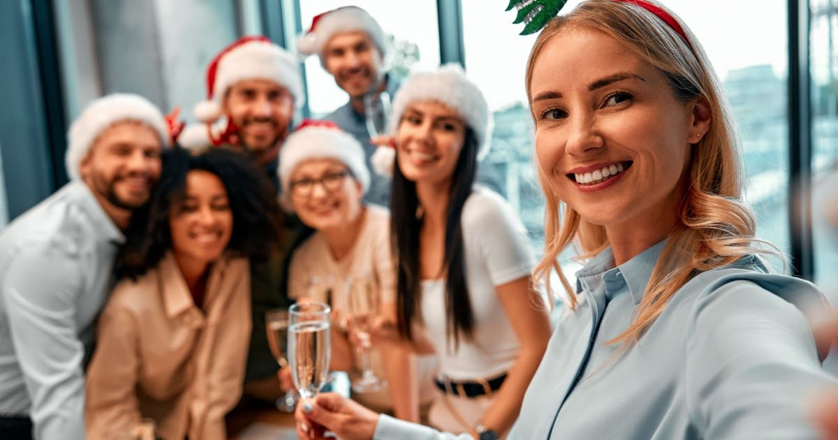 Grupo de pessoas usando chapéus de Papai Noel, sorrindo e celebrando juntos o Natal e o Ano-Novo.