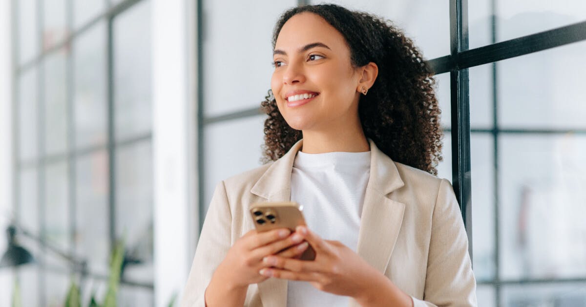 Uma mulher em um terno de negócios segurando um celular, demonstrando profissionalismo e modernidade.