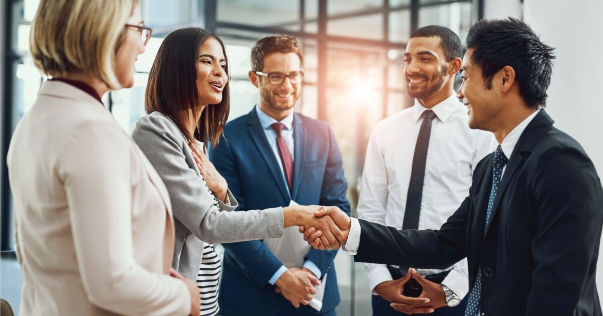 Empresários do mercado de franquias, reunidos em um ambiente corporativo, conversando e se cumprimentando.