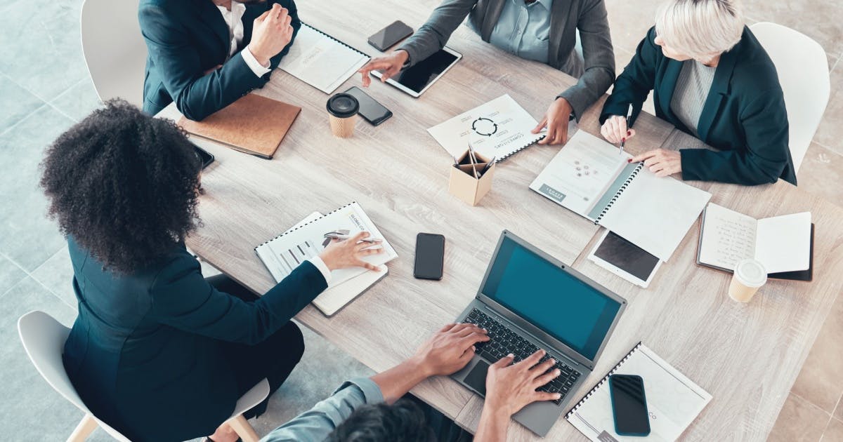 Equipe reunida em volta de uma mesa de escritório com alguns objetos, discutindo sobre a segurança jurídica de uma franquia.