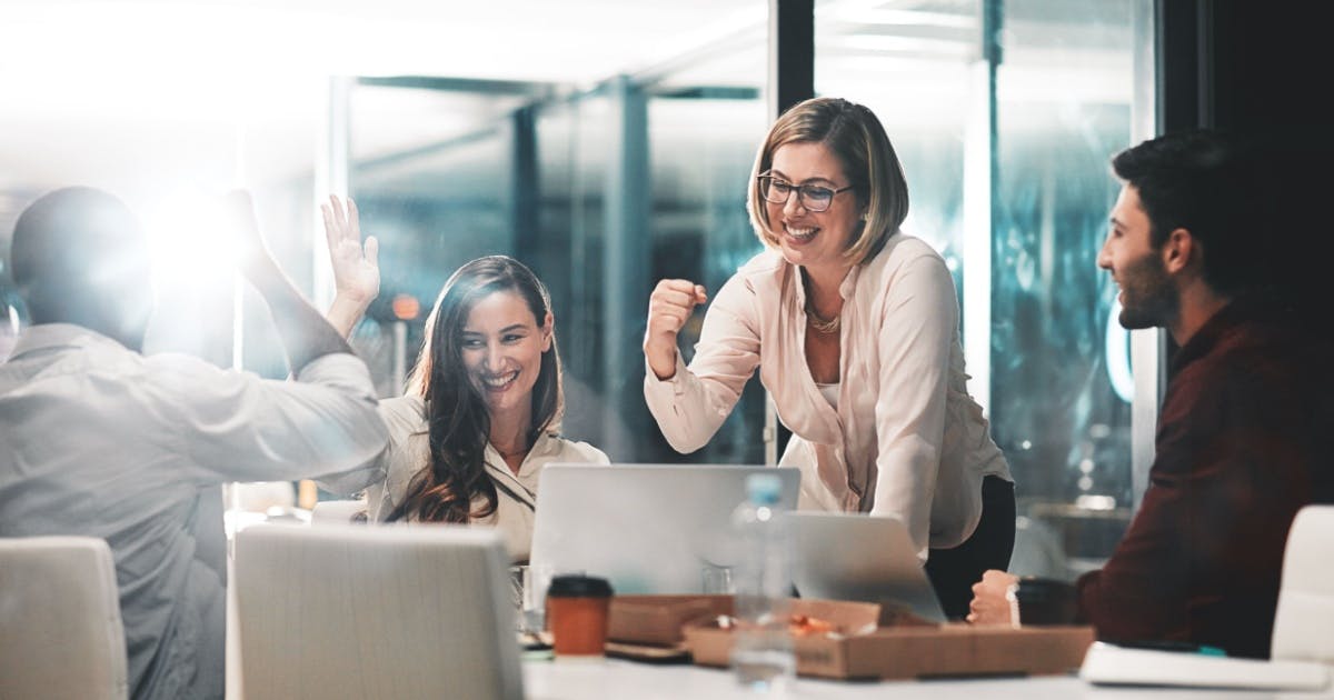 Equipe em uma sala de uma empresa, sorrindo e comemorando os resultados de franquias em alta.