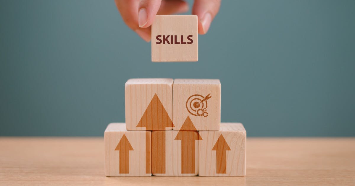 Uma pessoa empilha blocos de madeira com a palavra "habilidades" visível na frente.