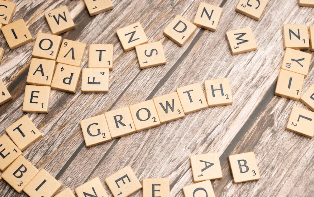 Blocos de madeira com letras em destaque formando a palavra “GROWTH” em uma superfície de tábuas antigas, conceito de aprendizado e evolução.