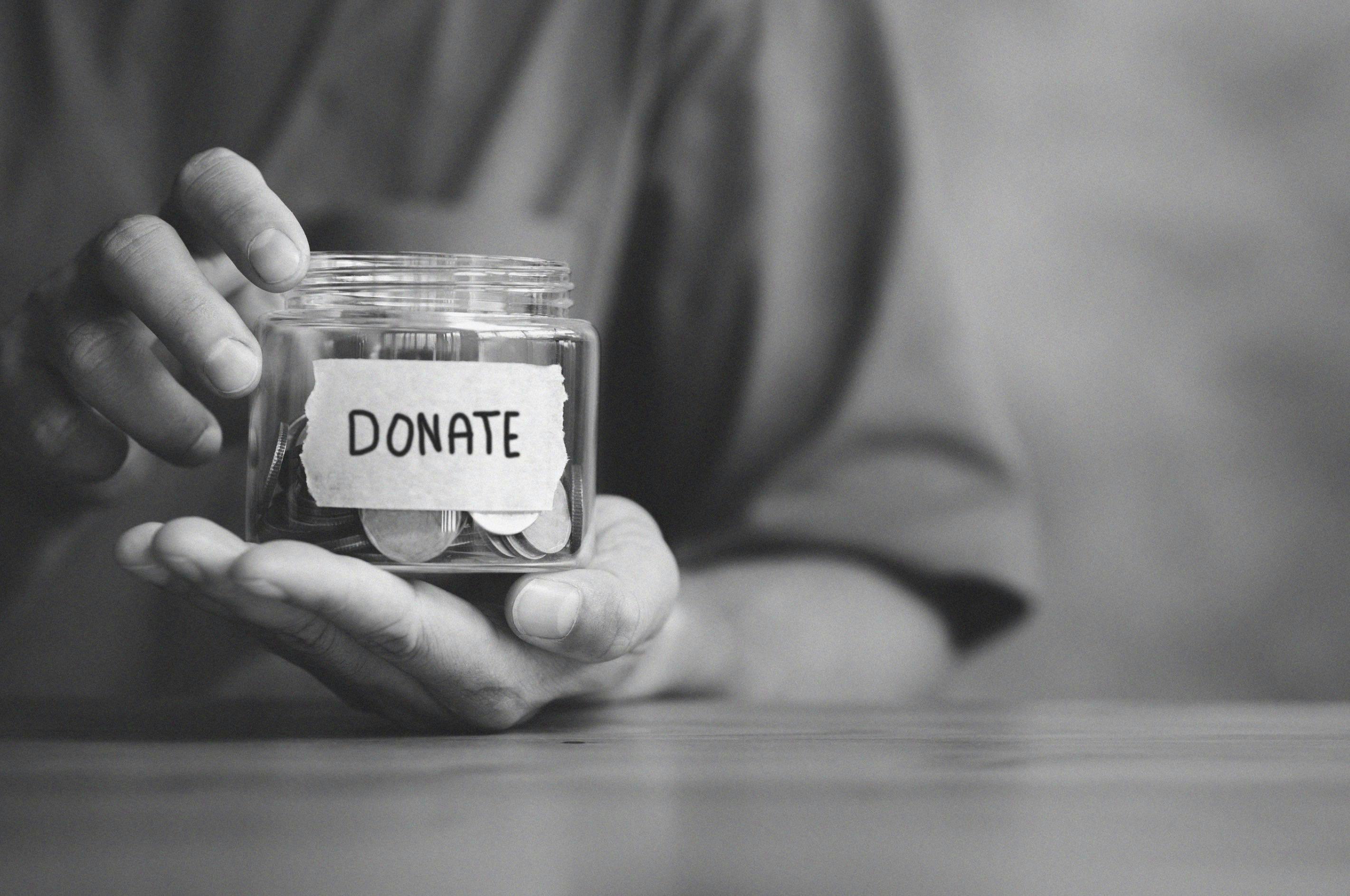 Hands holding a jar with Donate written on it. 