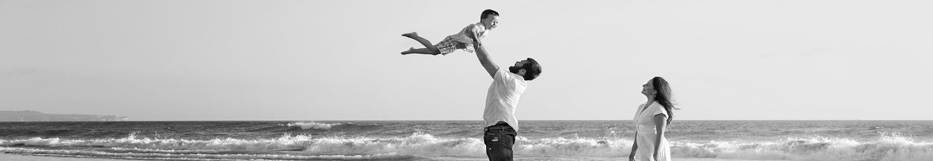 father holding son in the air on the beach 