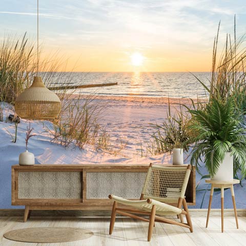 Fotobehang met strand, zee en duinen bij zonsondergang in een lichte woonkamer.