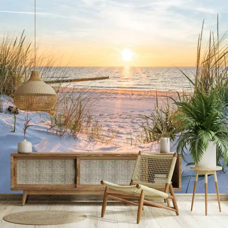 Fotobehang met strand, zee en duinen bij zonsondergang in een lichte woonkamer.