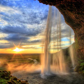 Fotobehang waterval bij zonsondergang in de bergen en de kleurrijke natuur.