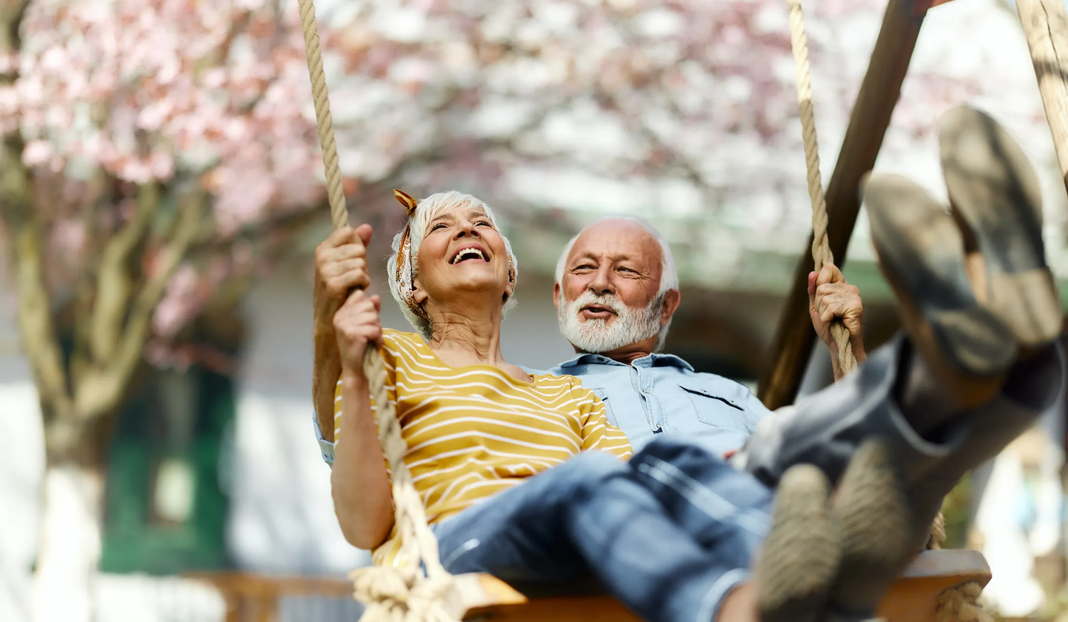 Happy senior couple swinging during spring day
