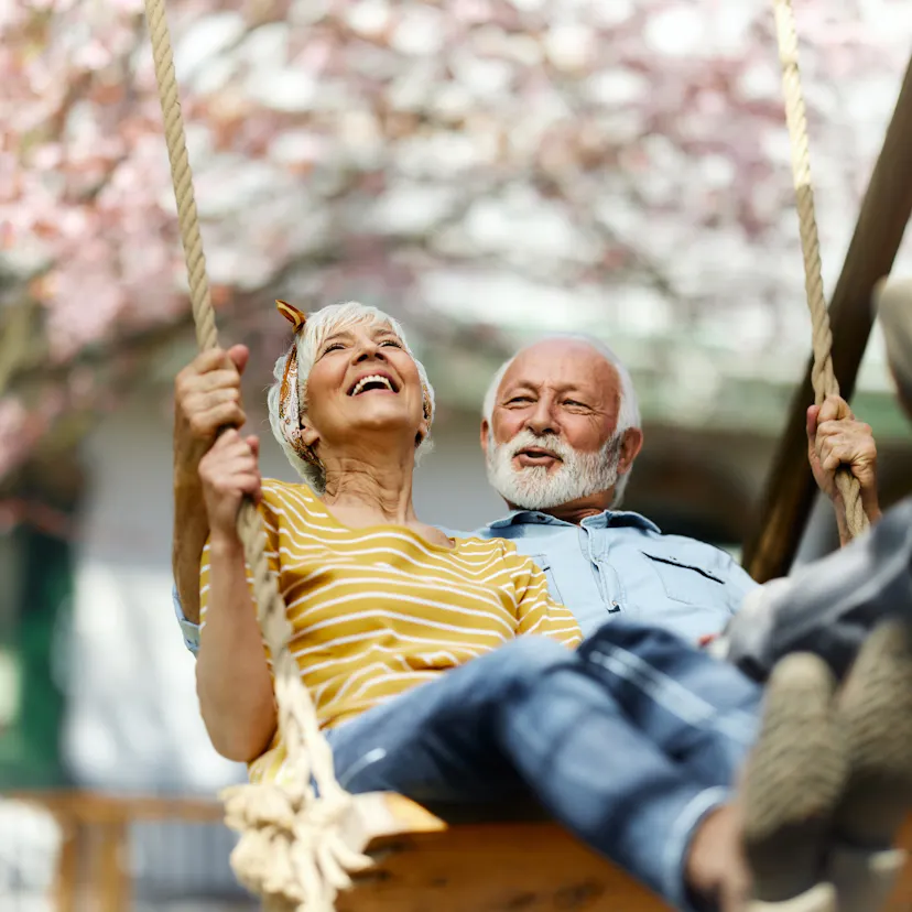 Happy senior couple swinging during spring day