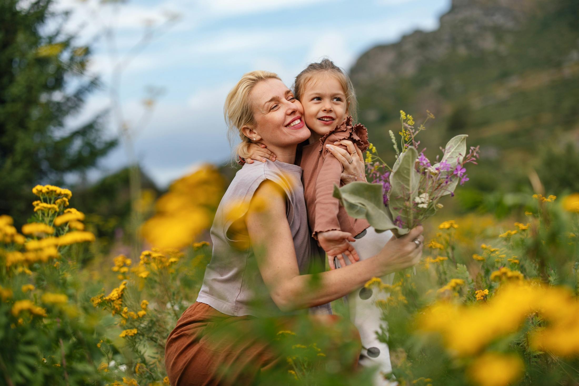 mother and daughter enjoying flowers in a meadow