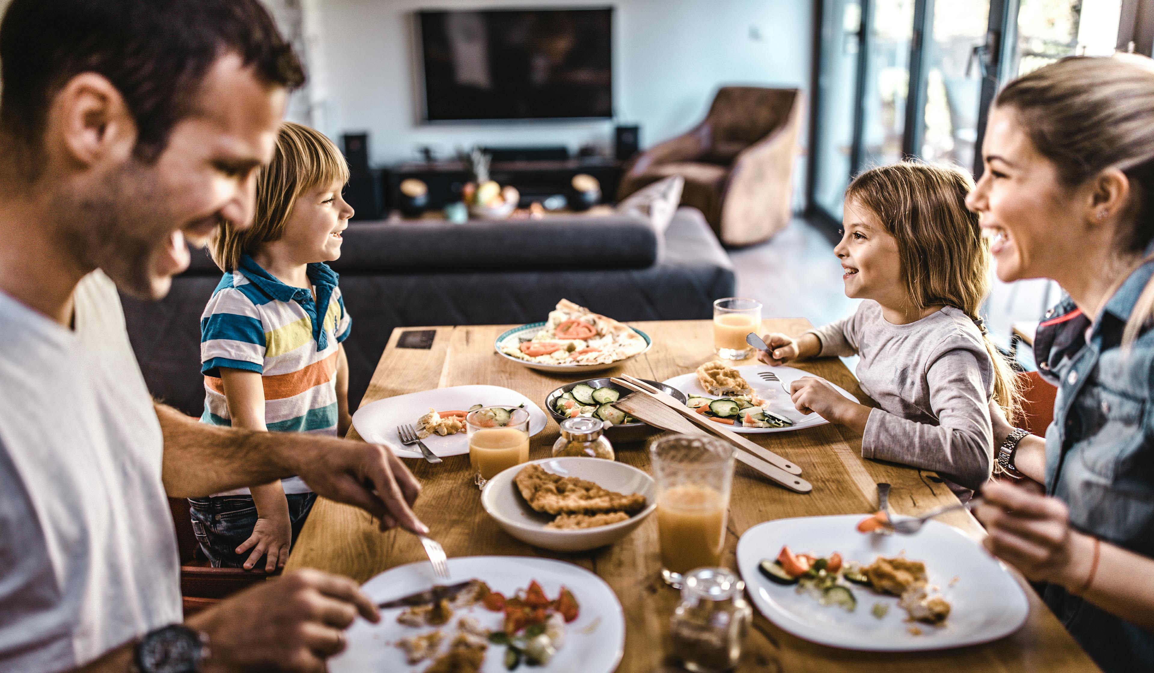 Young happy family talking while having lunch at dining table