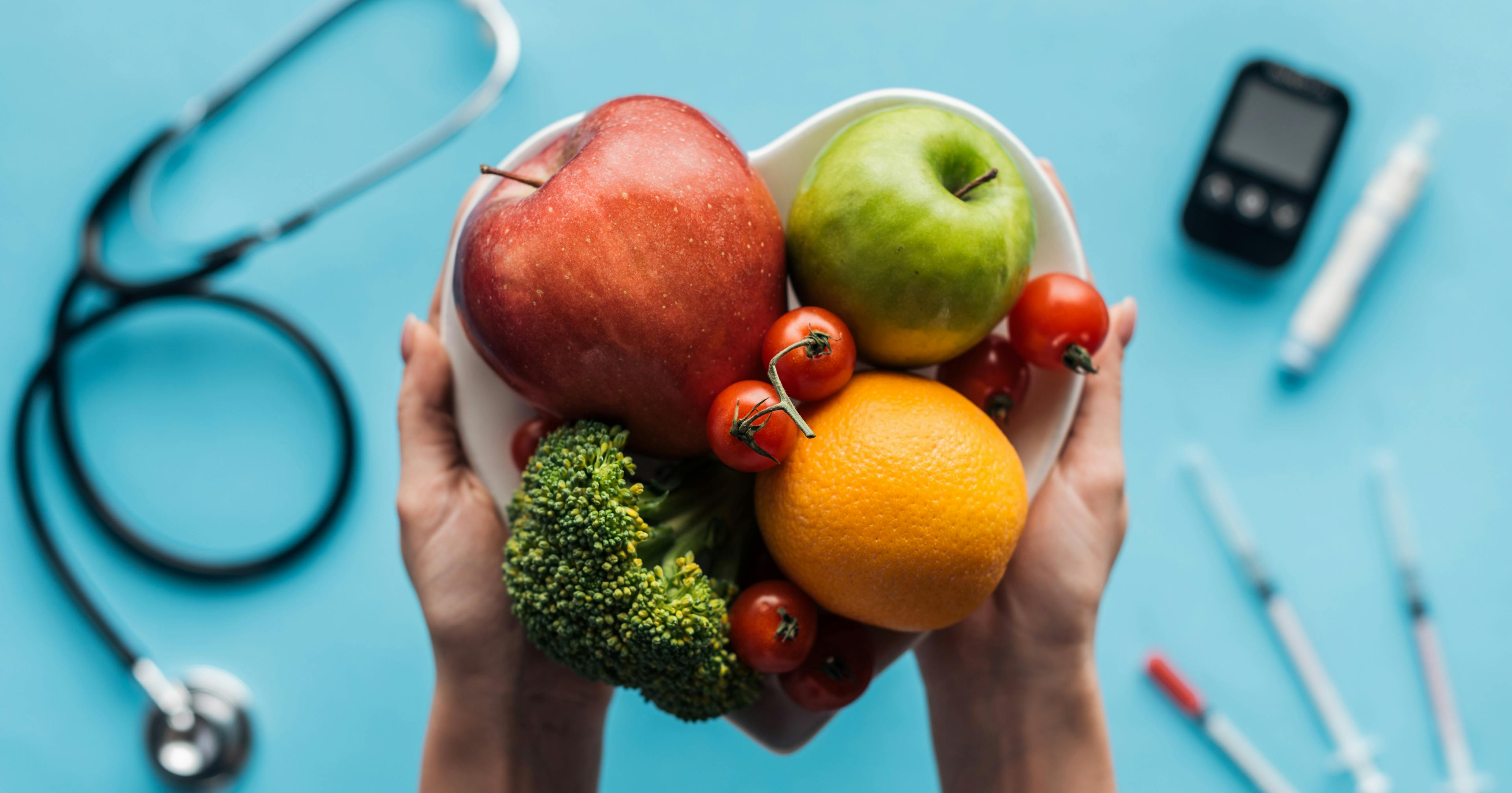 Fruits and vegetables in female hands with medical equipment on blue background