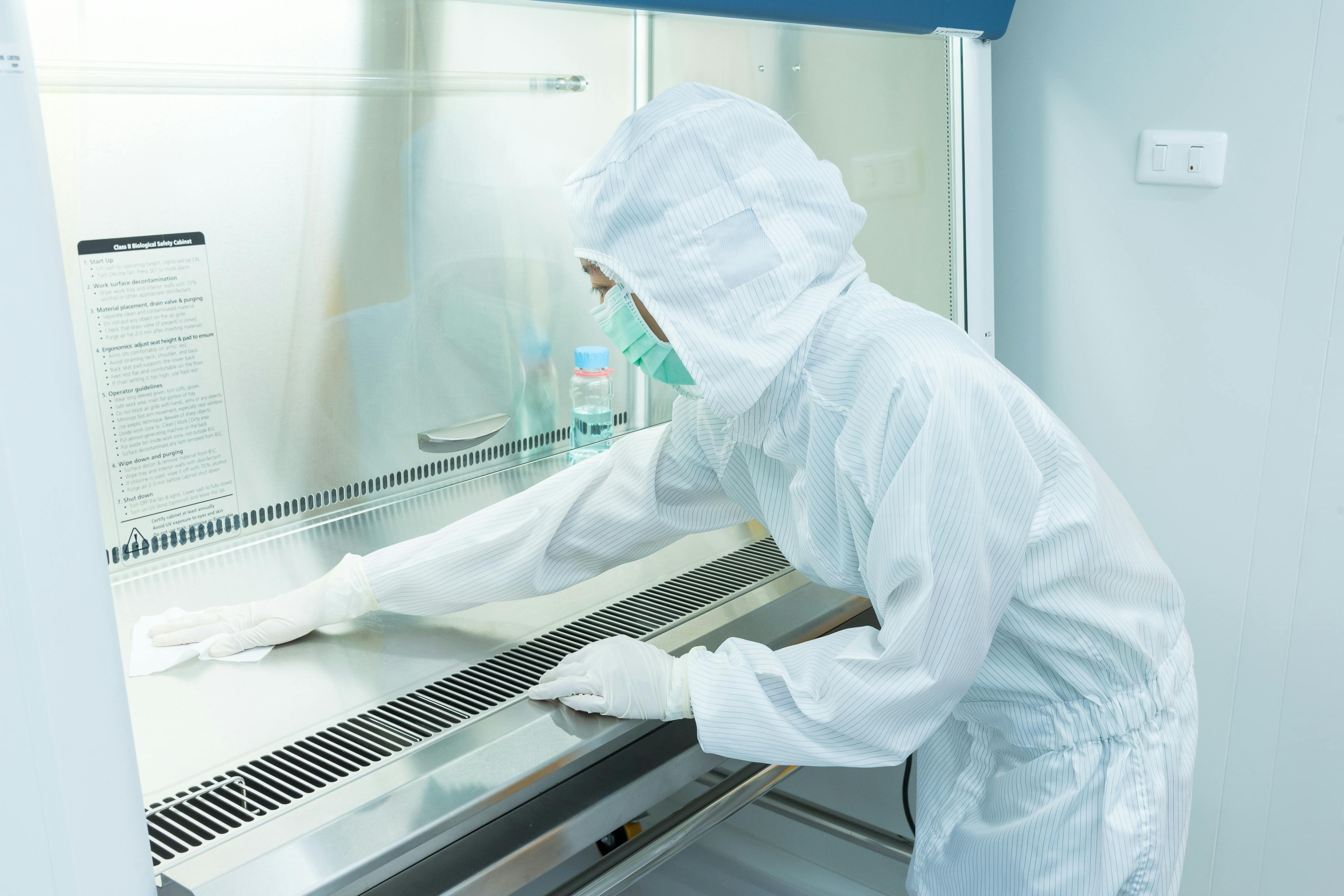 A scientist in sterile coverall gown using alcohol 70% and cleanroom wiper for cleaning Biological Safety Cabinet (BSC)