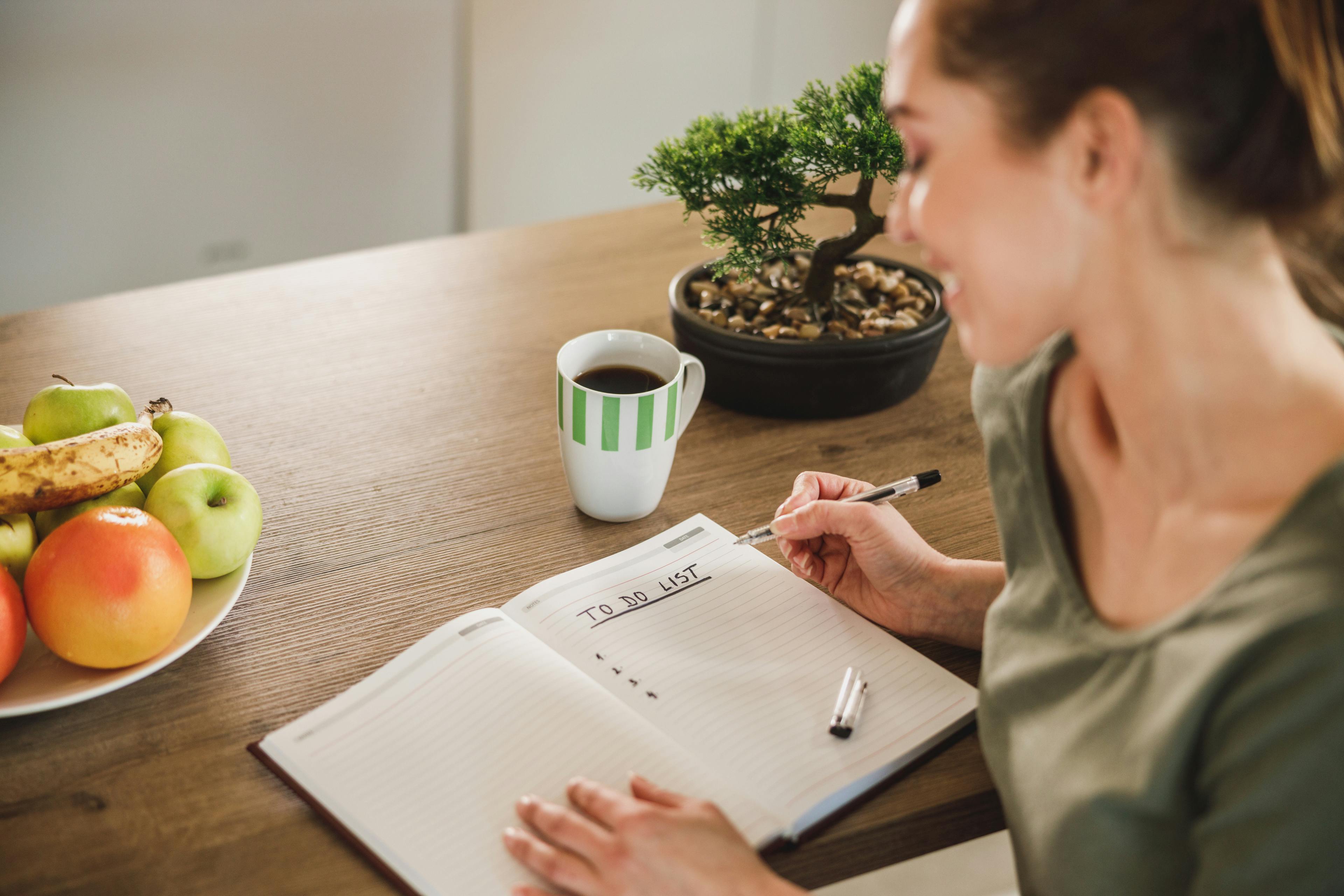 Woman Making To Do List While Enjoying Morning Coffee