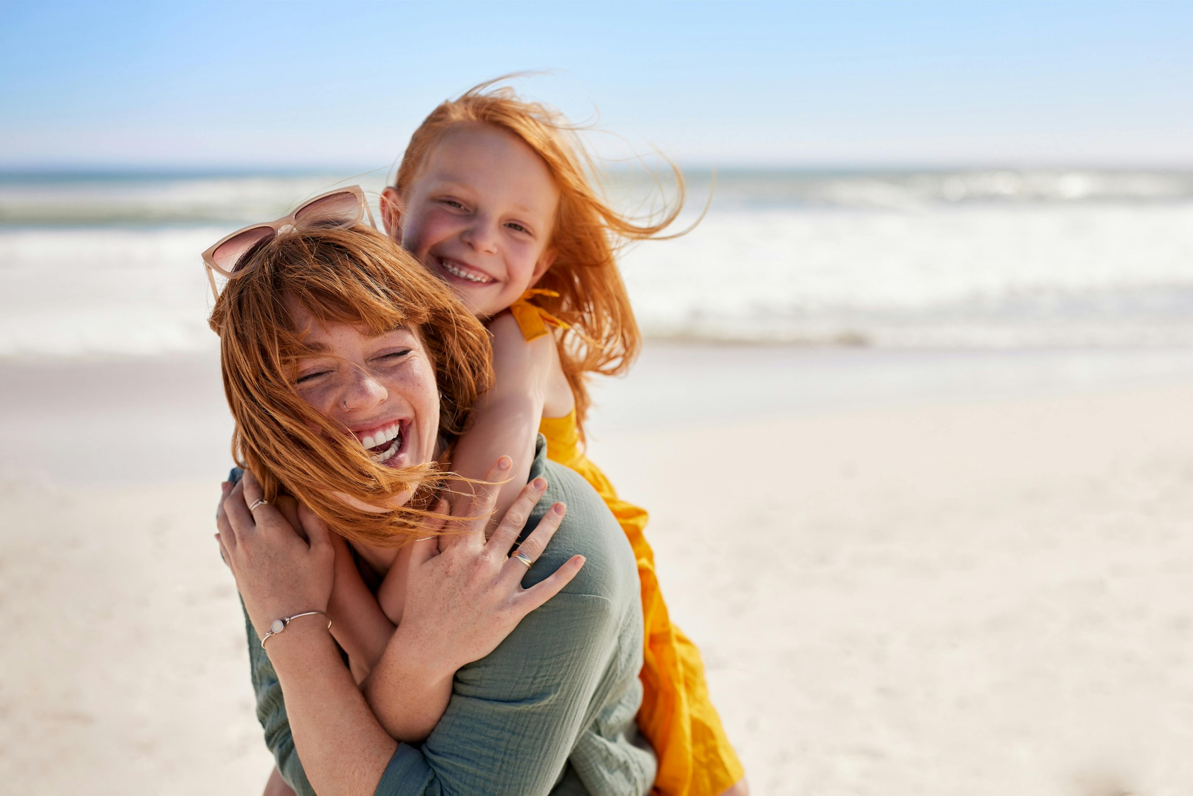 joyful young woman on the beach with her daughter