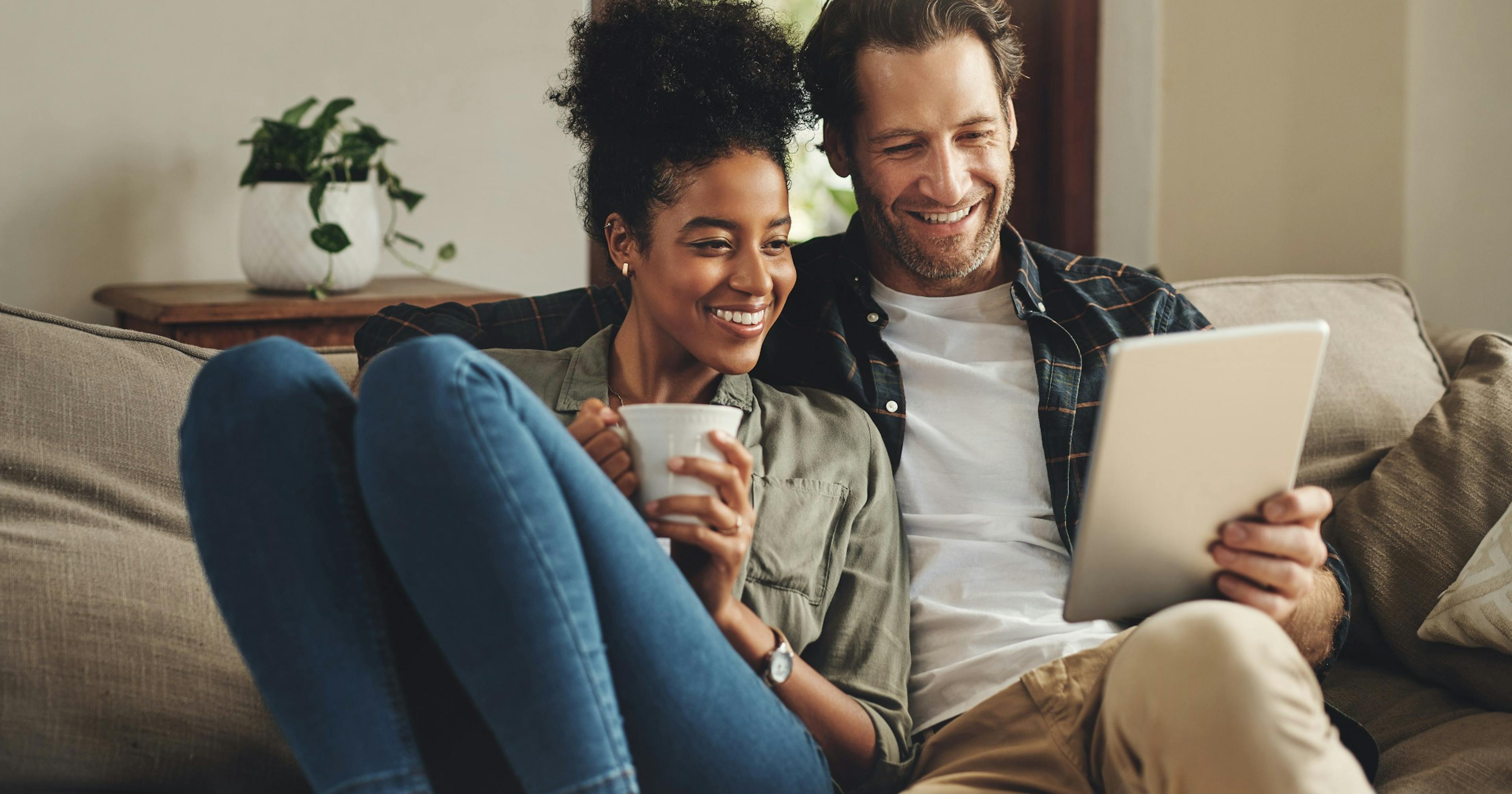 couple relaxing on couch looking at tablet